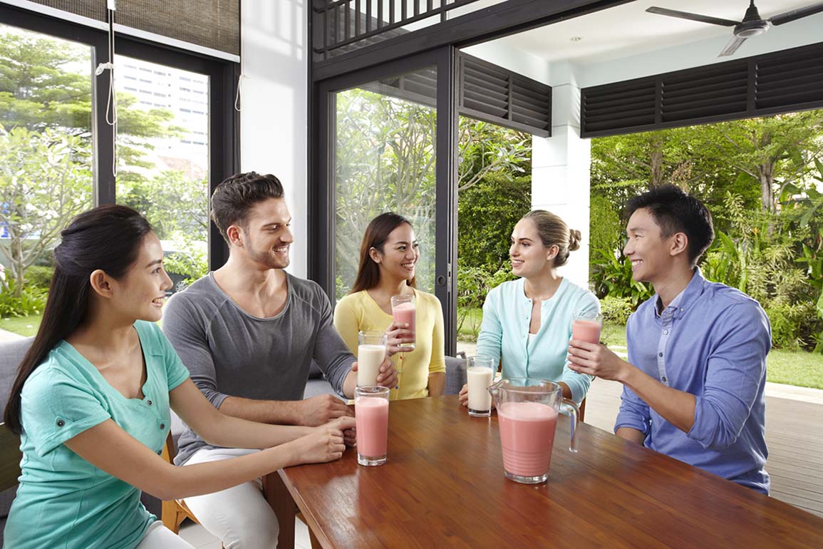 Група приятели се усмихват и вдигат шейкове след тренировка.